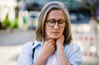A woman with glasses and a neck brace. She is looking at the camera. Concept of discomfort and pain
