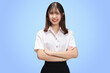 Portrait Asian student girl with Thai university uniform cross arms isolated on blue background.