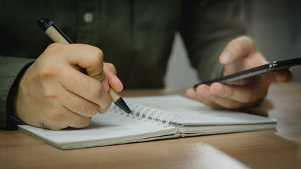 Wall Mural - businessman working at work table,home office desk background, checklist writing planning investigate enthusiastic concept. Male hand taking notes on the notepad.	