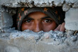 Arab woman a refugee or migrant, is peering through a hole in a cement wall, possibly trying to cross a border or escape a migration crisis situation