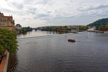 Wall Mural - Scenic view of Moldova River with skyline of City of Prague and bridges in the background on a cloudy autumn day. Photo taken October 10th, 2023, Prague, Czech Republic.