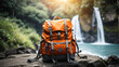 Orange hiking backpack on the background of a waterfall in the rainforest. Travel, trekking tour to wild, exotic places, tourism, outdoor activities. 