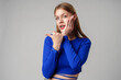 Woman in Blue Top Pointing With Hand Against Neutral Background