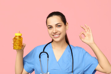 Sticker - Portrait of female doctor with pills showing OK on pink background