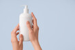 Female hands with bottle of natural cream on color background, closeup