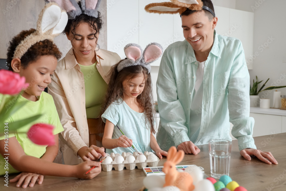 Happy family painting eggs in kitchen on Easter Day