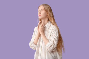Wall Mural - Beautiful young woman praying on purple background