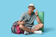 © Pixel-Shot - Young male tourist with photo camera pointing up on blue background
