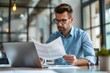 © SHI - A busy young professional businessman checks documents on his laptop in his office. Serious business accounting experts in the workplace read legal documents overview of company documents.