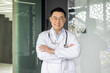 © Liubomir - Portrait of Asian successful head doctor of clinic, man in white medical coat with stethoscope smiling and looking at camera with crossed arms