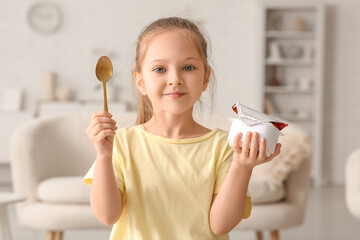 Wall Mural - Cute little girl with spoon and yogurt at home