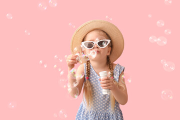 Sticker - Cute little girl in hat and sunglasses blowing soap bubbles on pink background