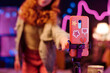 Closeup shot of unrecognizable Caucasian girl with red hair adjusting smartphone camera on tripod in her room, copy space