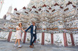 © tonjung - Asian couple happy tourists to travel on they holidays and holding in Wat Arun Temple in Bangkok, Thailand.holiday concept.