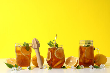 Wall Mural - Cold tea with orange slices and mint leaves on a yellow background