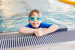 Cute preschool child, boy, swimming in swimming pool, wearing wetsuit