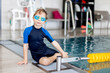 Cute preschool child, boy, swimming in swimming pool, wearing wetsuit