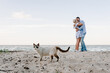 View of cat. Man embraces woman on sand sea. Female kisses male on beach ocean and enjoys sunny summer day. Couple in love hugging and kissing each other on seashore. Spending time together.