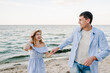 Female and male run on beach ocean and enjoy summer day. Happy couple in love holding hands and looking at each other on seashore. Man and woman running on sand sea. Spending time together. Closeup.