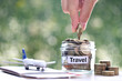 Stack of coins money in the glass bottle and airplane on passport with natural green background,Saving planning for Travel budget of holiday concept