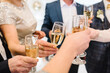 Cheers. People celebrate and raise glasses of wine for toast. Group of man and woman cheering with champagne. Closeup.