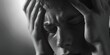 A dramatic black and white photo of a man holding his head. Perfect for illustrating stress or headache concepts