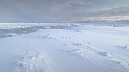 Wall Mural - Infinitely, endless polar snowy desert in Antarctica. Frozen iceberg. South Pole frost surface. Scientific base. Snow covered mountains on horizon. Aerial view flight. Ice Landscape. Winter frozen