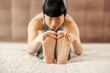 Close up of japanese woman practicing yoga and stretching. Selective focus on feet.