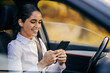 A happy woman is using her phone in a car.