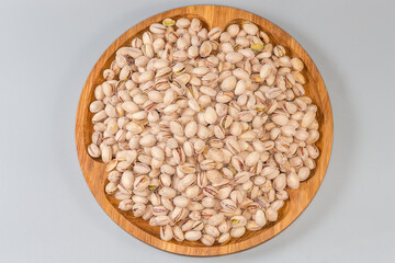 Wall Mural - Pistachio nuts on wooden dish on gray background, top view