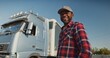 Portrait of happy african american employee standing and looking at camera. Attractive male truck driver in cap and shirt working at logistics company. Professional transportation concept.