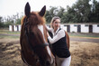 A beautiful woman in jockey clothes and a brown horse