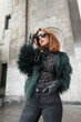Beautiful glamorous fashion woman model with sunglasses in a fashionable shaggy jacket with a leopard T-shirt in the city near a vintage building