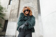 Glamorous beautiful vogue woman with cool sunglasses in a fashion shaggy jacket posing in the city