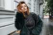 Stylish beautiful fashion woman model with red hair in fashionable clothes in the city
