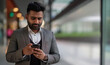 © Pier Fax - Indian businessman uses smartphone. Technologies, connectivity, messaging. career, success. Rich elegant man with gray jacket.