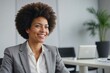 Confident African-American businesswoman in office setting with green plant in background, smiling away from camera on corporate interview