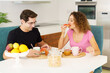 Happy adult couple having healthy breakfast at dining table at home