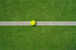  A yellow tennis ball lies on the green court. Big panorama.