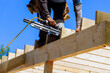 Framer worker installing beams using air nails hammer in nailing wooden frame