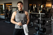 © Home-stock - Sporty man holding water bottle and towel after sport workout at modern gym, guy relaxing after training in fitness club, smiling at camera