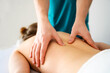 Girl during back massage in spa salon. Masseur hands doing care body therapy procedure for young woman wellness and relaxation.