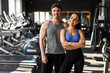 © Home-stock - Fitness muscular couple posing in gym, strong couple standing in sports center surrounded by exercise equipment and smiling at camera