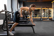 © Home-stock - Muscular bodybuilder man doing exercises with weights, lifting dumbbells at bench in gym interior, side view, free space