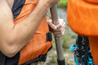 Selective focus on the orange life jacket of the tour guest holding a paddle handle before getting into the boat. To raft in the fierce river