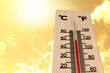 Heatwave and hot weather impact, thermometer with orange sky and sun background.
