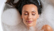 Close-up and top view of an attractive lady with eyes close lying in bath with foam. Relaxation, health and skin care in bathroom, spa, concept. Generative Ai.