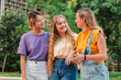 Three teenage gossip girls talking together outside. Group of multiracial female friends chatting and having communication. Young adult student women smiling and walking together on a social meeting