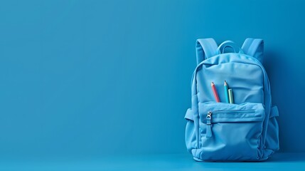 A full school backpack with books and supplies inside isolated on a blue background with copy space for a Back to School concept.