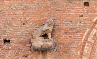 Wall Mural - Architectural detail featuring a stone lion sculpture on a brick wall in Bologna. The sculpture sits on a base, adding a decorative aspect to the building exterior